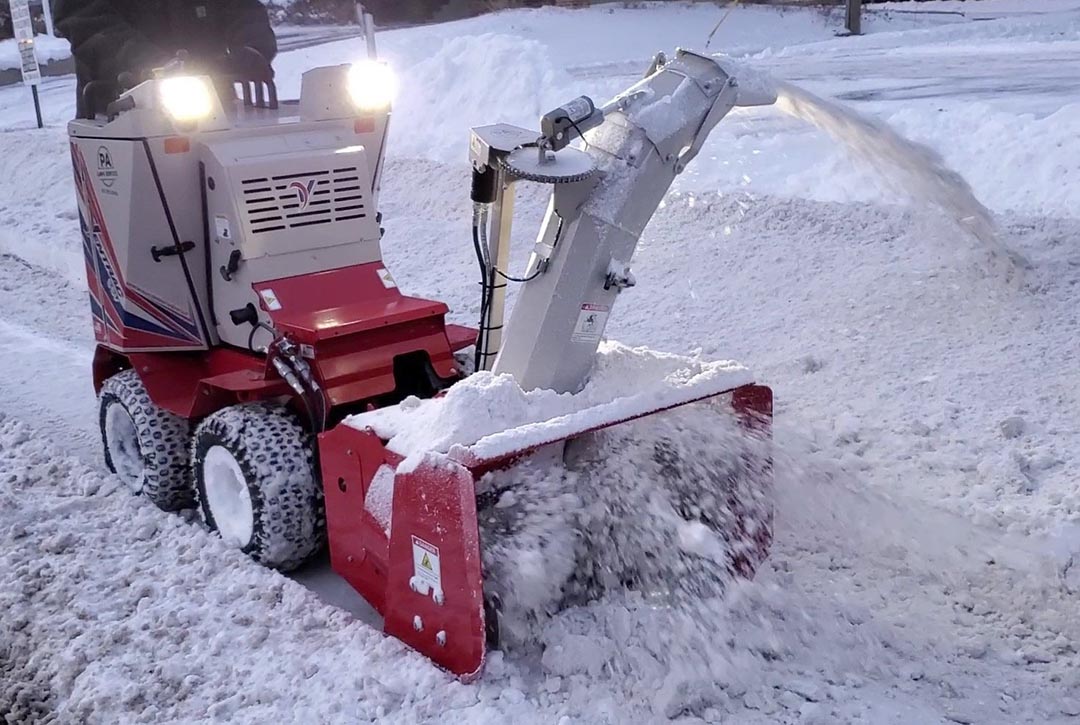 Picture of an Employee removing snow from a sidewalk with a commercial unit #2
