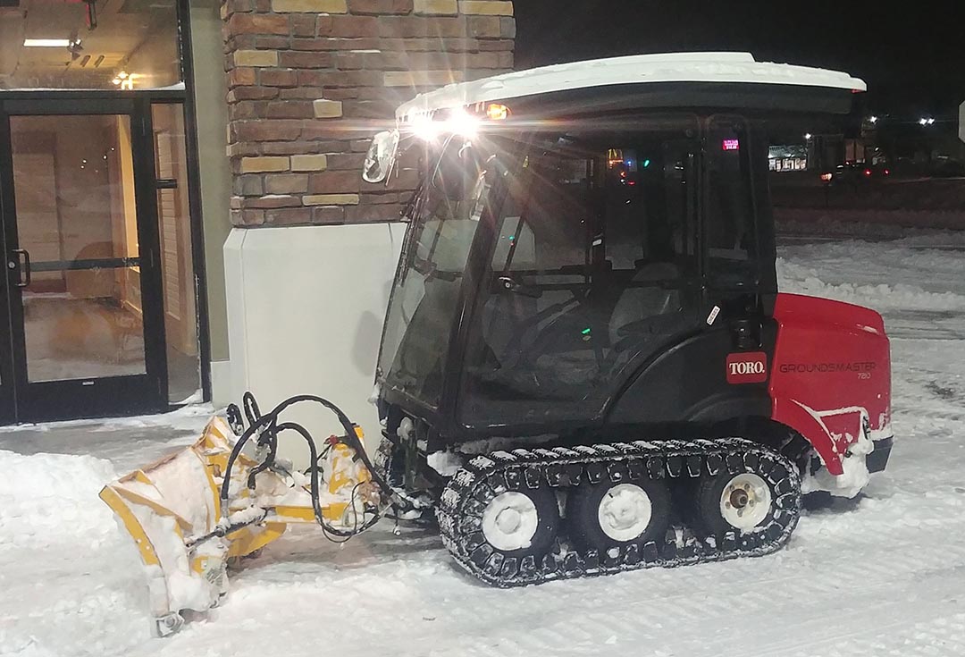 Picture of an Employee removing snow from a sidewalk with a commercial unit #3