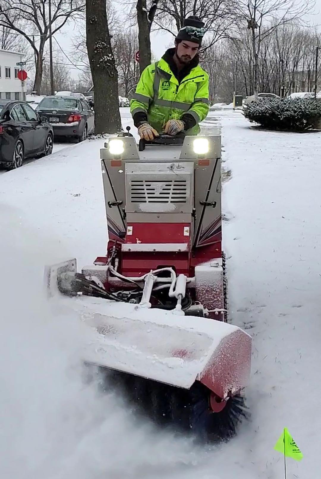 Picture of an Employee removing snow from a sidewalk with a commercial unit