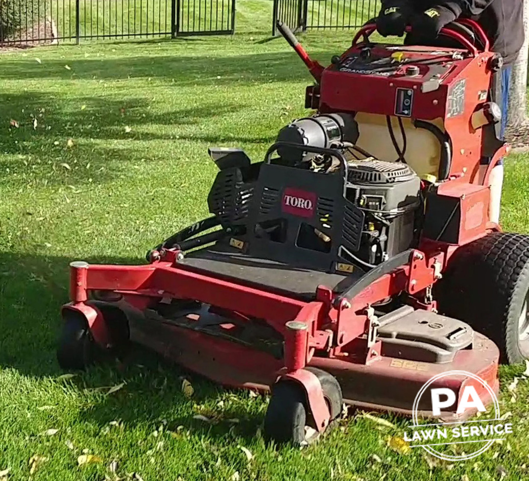 A clean, raked lawn after a professional fall cleanup, with garden beds tidied.